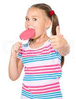 Little girl with lollipop showing thumb up gesture