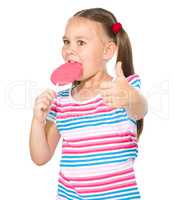 Little girl with lollipop showing thumb up gesture