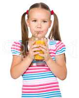 Little girl is drinking carrot juice