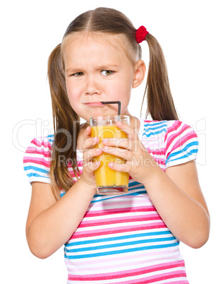 Little girl unwillingly drinking orange juice