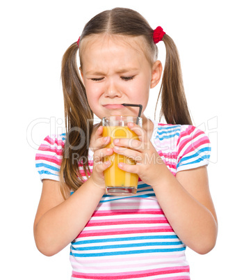 Little girl unwillingly drinking orange juice