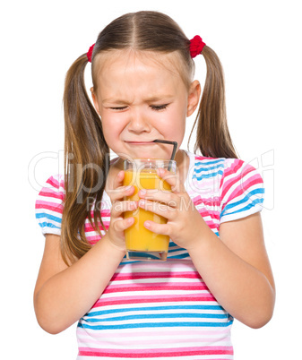 Little girl unwillingly drinking orange juice