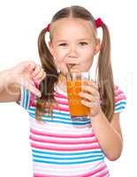 Little girl is drinking carrot juice