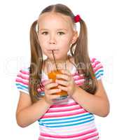 Little girl is drinking carrot juice