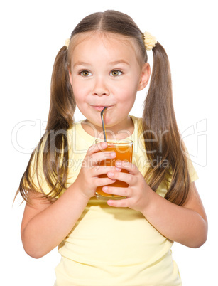 Little girl is drinking carrot juice