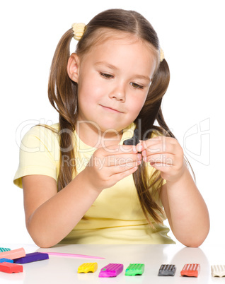 Little girl is playing with plasticine