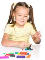 Little girl is playing with plasticine