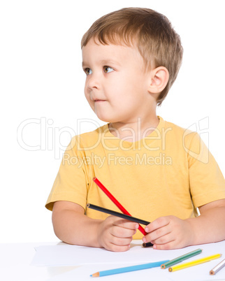 Little boy is drawing using color pencils