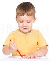 Little boy is drawing using color pencils