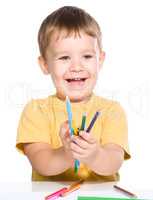 Little boy is playing with color pencils