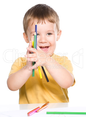 Little boy is playing with color pencils