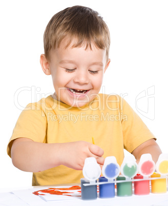 Little boy is playing with paints