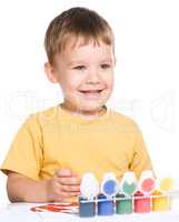 Little boy is playing with paints