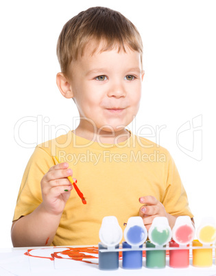 Little boy is playing with paints