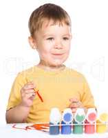 Little boy is playing with paints