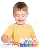 Little boy is playing with paints