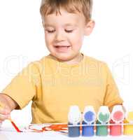 Little boy is playing with paints