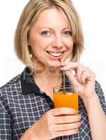Young woman is drinking carrot juice