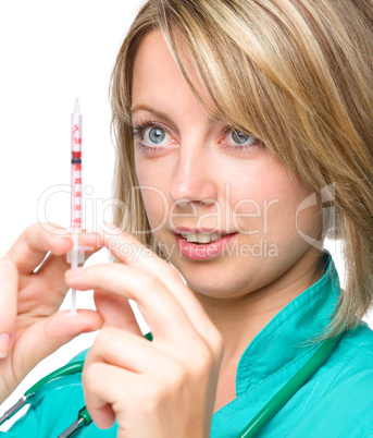 Young nurse is preparing syringe for injection