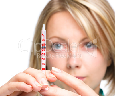 Young nurse is preparing syringe for injection