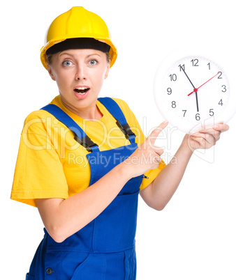 Young construction worker is pointing at clock