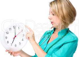 Young lady doctor is holding clock showing seven