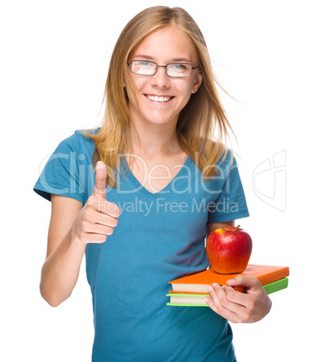 Young student girl is holding book and apple