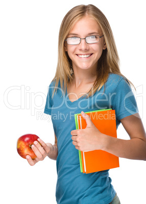 Young student girl is holding book and apple