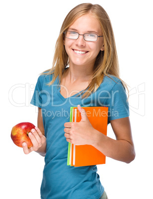 Young student girl is holding book and apple