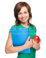 Young student girl is holding book and apple