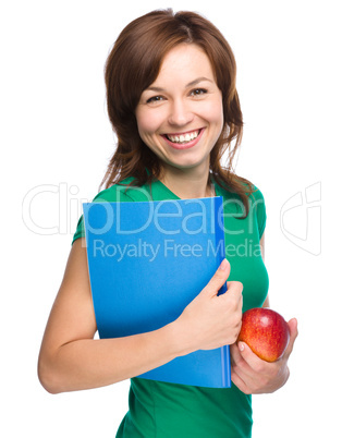 Young student girl is holding book and apple