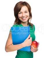 Young student girl is holding book and apple