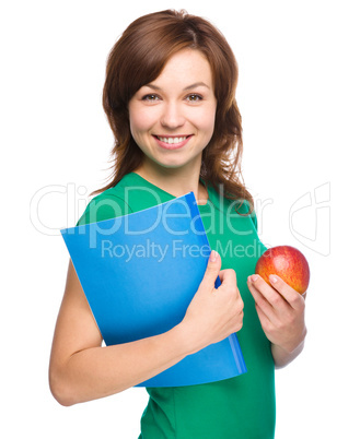 Young student girl is holding book and apple