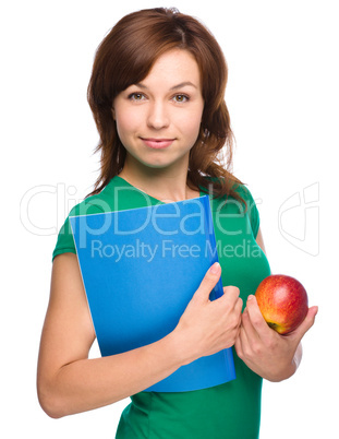 Young student girl is holding book and apple