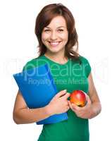 Young student girl is holding book and apple