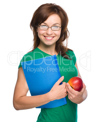 Young student girl is holding book and apple