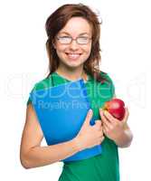 Young student girl is holding book and apple