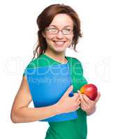 Young student girl is holding book and apple