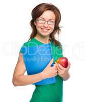 Young student girl is holding book and apple