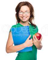 Young student girl is holding book and apple