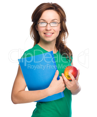 Young student girl is holding book and apple