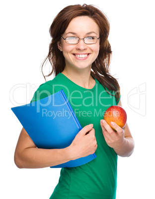 Young student girl is holding book and apple