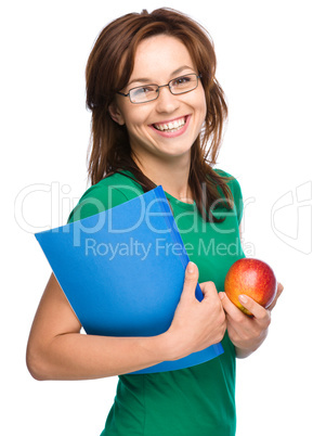 Young student girl is holding book and apple