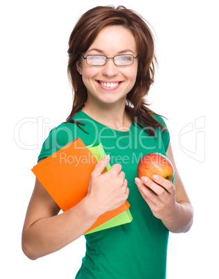 Young student girl is holding book and apple