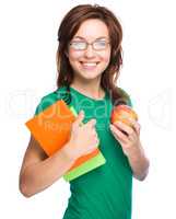 Young student girl is holding book and apple