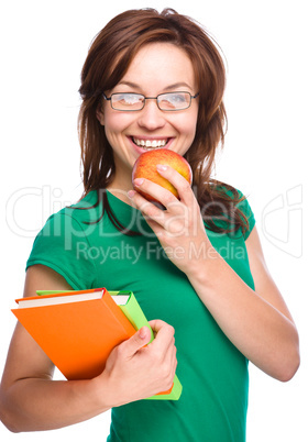 Young student girl is holding book and apple