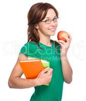 Young student girl is holding book and apple