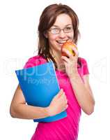 Young student girl is holding book and apple