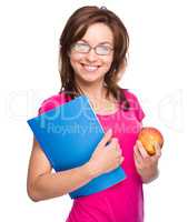 Young student girl is holding book and apple