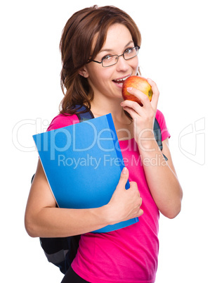 Young student girl is holding book and apple